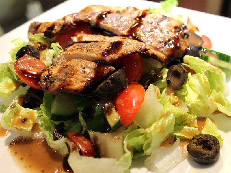 Grilled chicken salad with tomatoes, olives, and balsamic glaze.