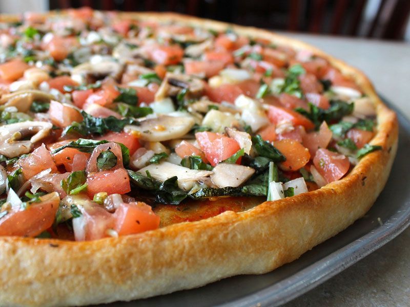Pizza with tomatoes, mushrooms, and herbs on a thick crust.