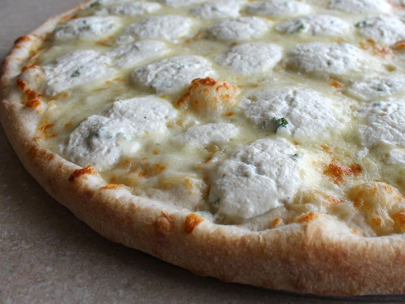 White pizza with large dollops of ricotta cheese, melted mozzarella, and a golden crust.