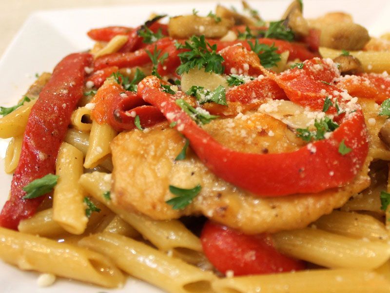 Penne pasta with chicken, red peppers, mushrooms, and Parmesan cheese, garnished with parsley.