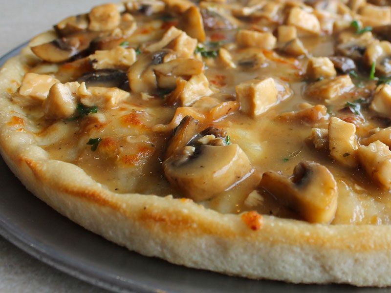 Pizza with mushrooms and chicken, close up on a grey plate, golden crust.