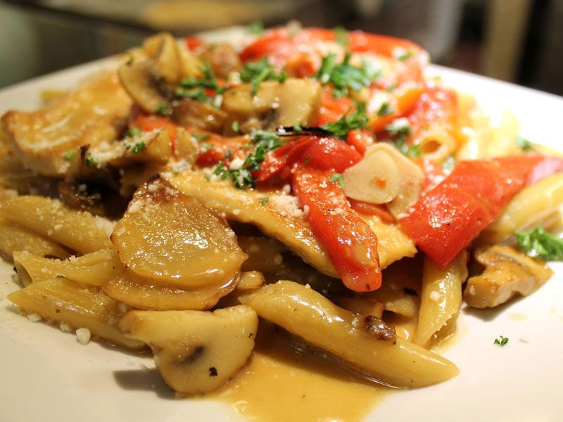 Pasta dish with chicken, mushrooms, red peppers, and parsley.