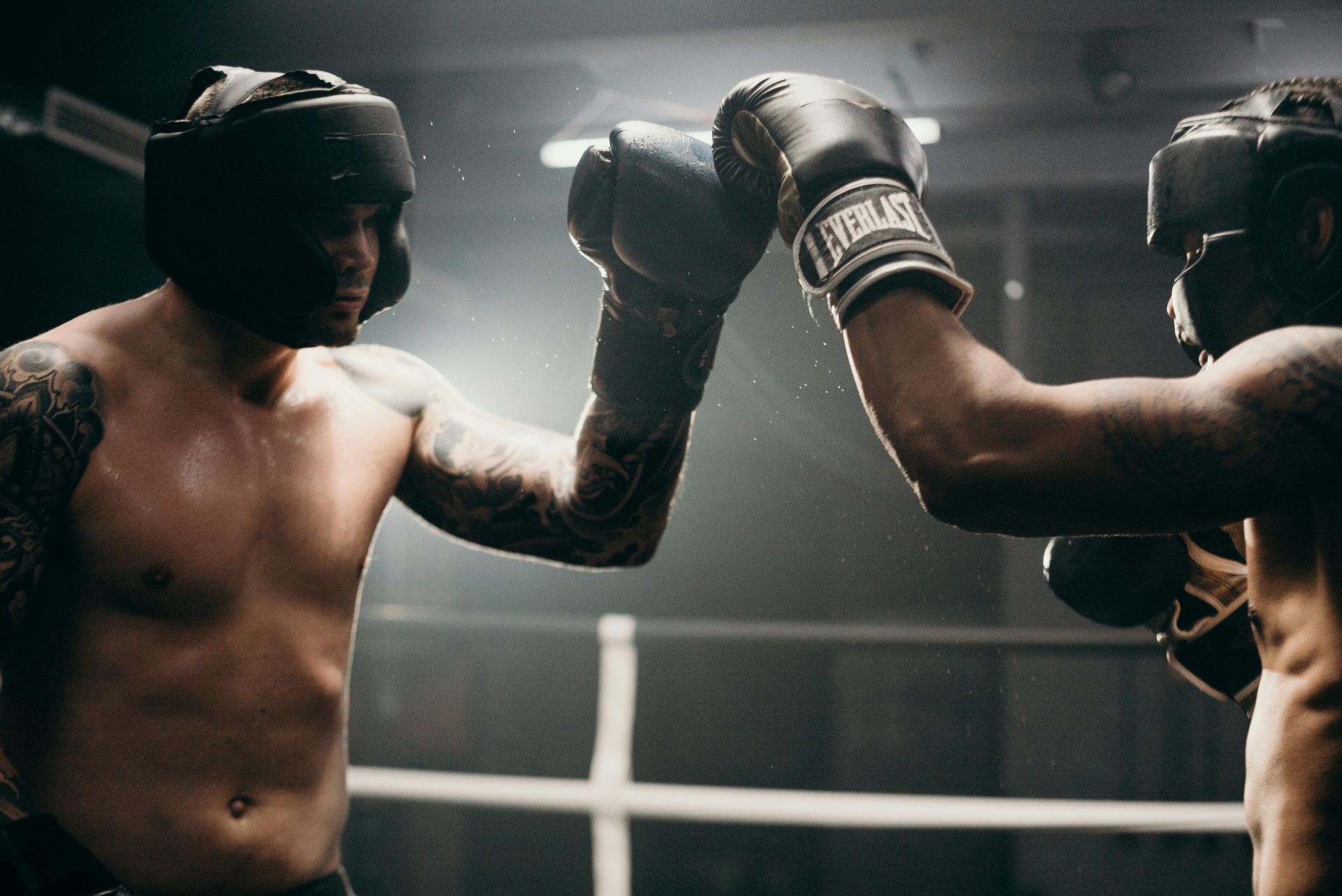 Two boxers sparring in a dimly lit ring, gloves raised and facing off