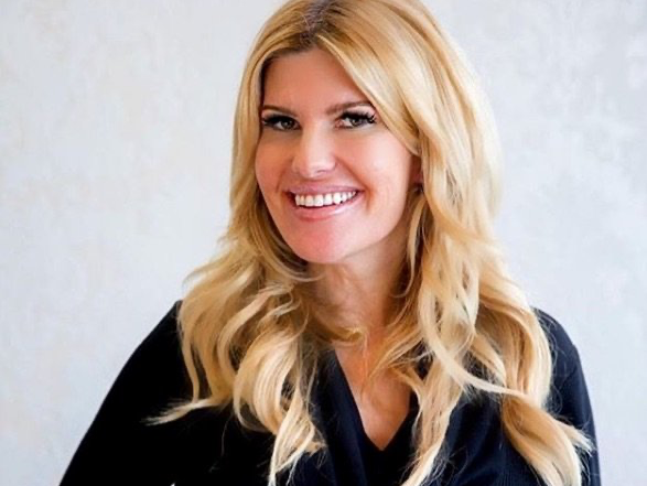 A woman with blonde hair is smiling and wearing a black shirt.