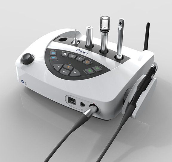 White medical device with various tools and controls, including handpieces, likely used for dental or medical procedures.