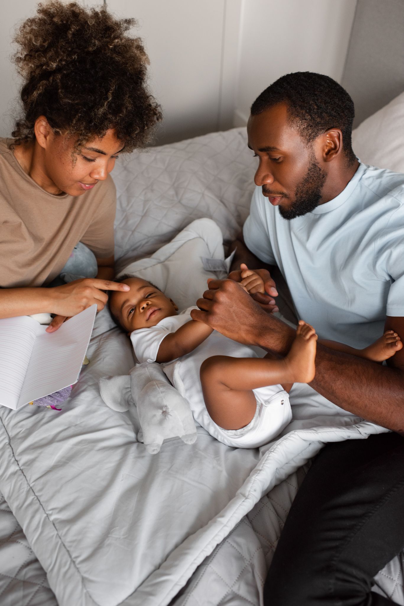 A man and woman are laying on a bed with a baby.