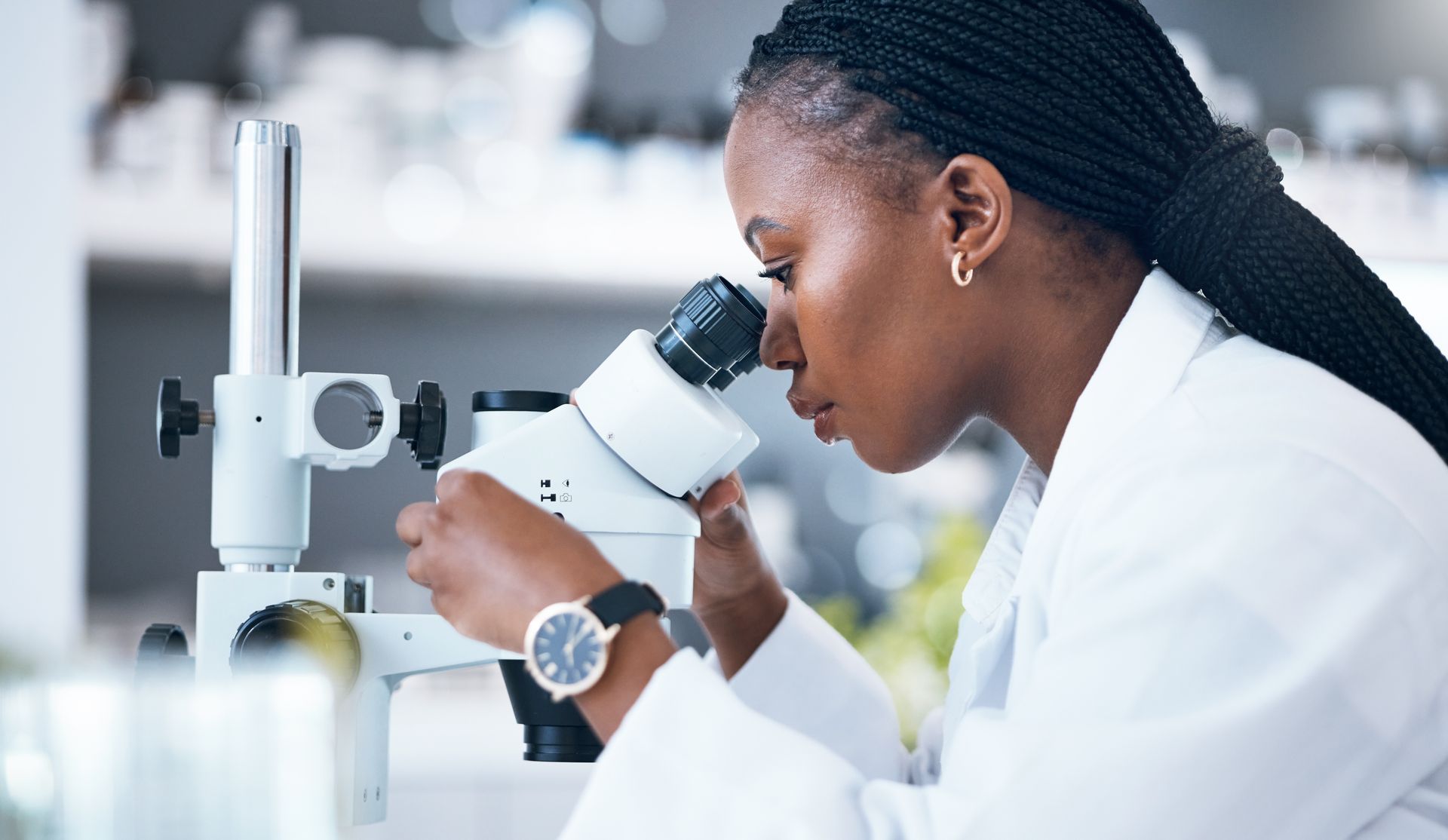 A woman is looking through a microscope in a laboratory.