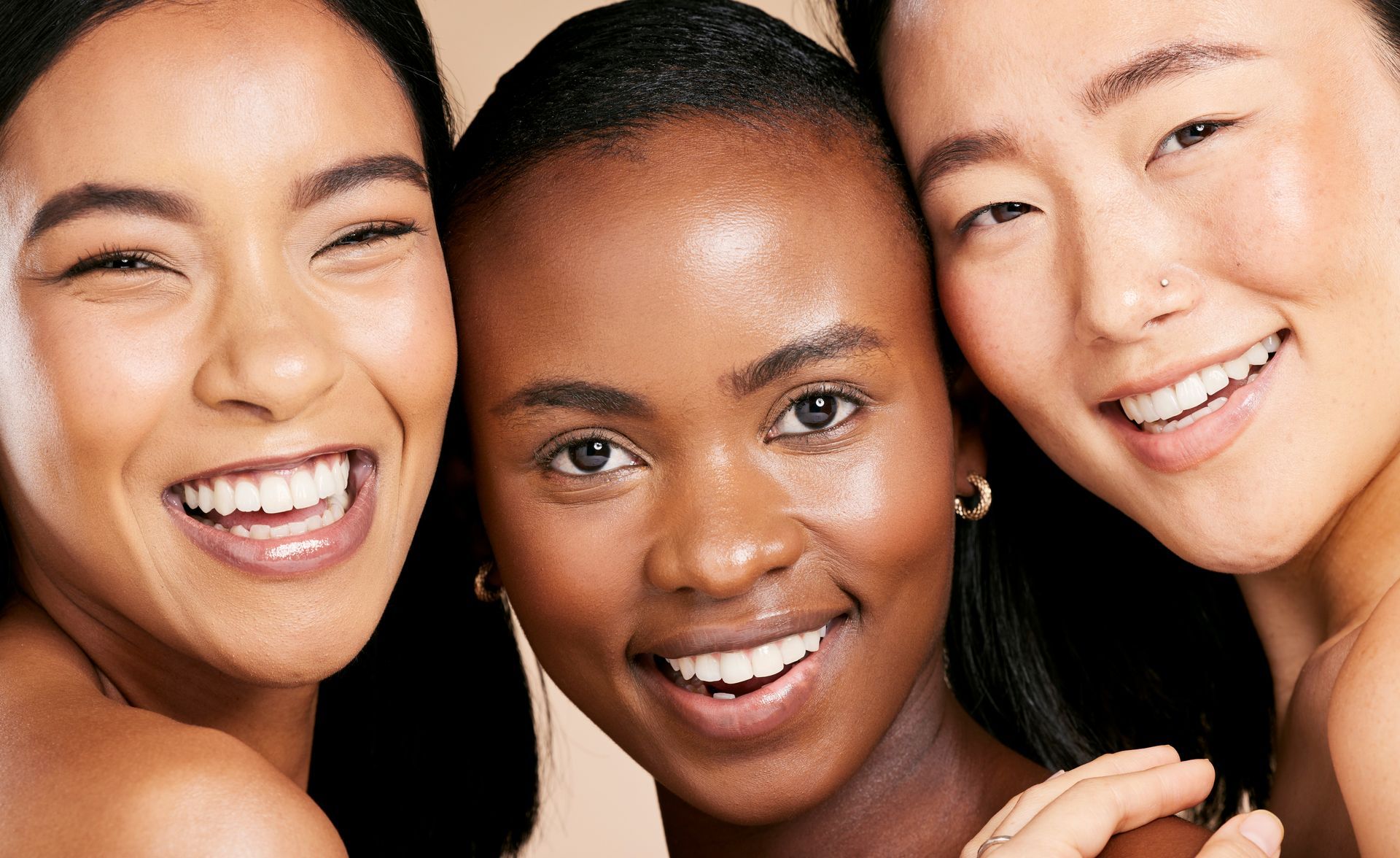 Three women of different races are smiling for the camera.