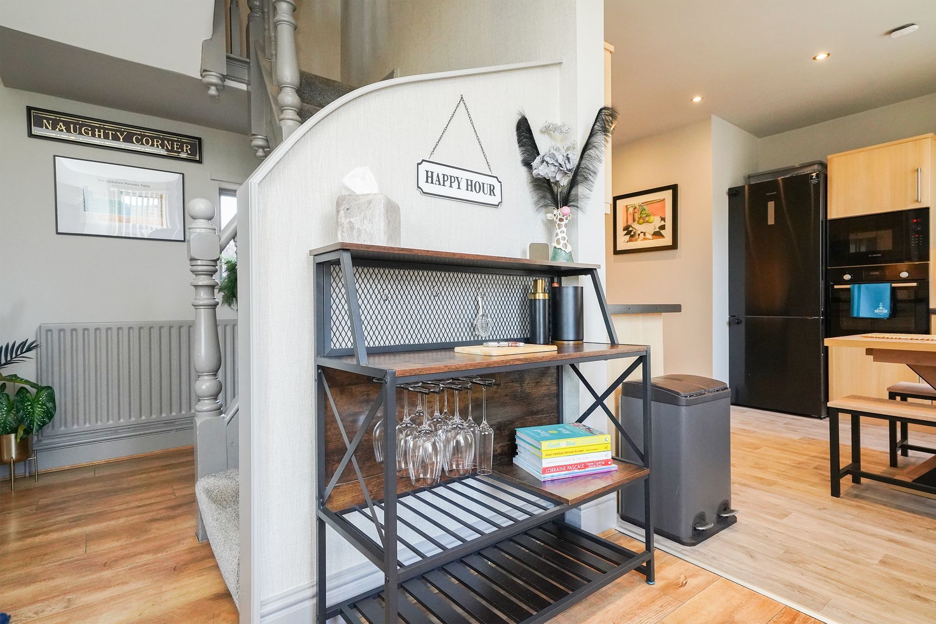 Interior hallway with black shelving unit, rustic decor, radiator, and open kitchen in background