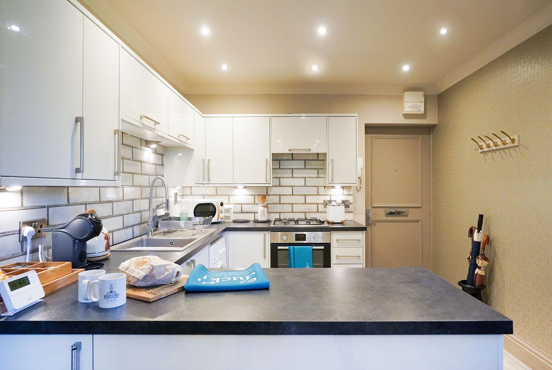 Modern white kitchen with black countertops, central island, and warm recessed lighting