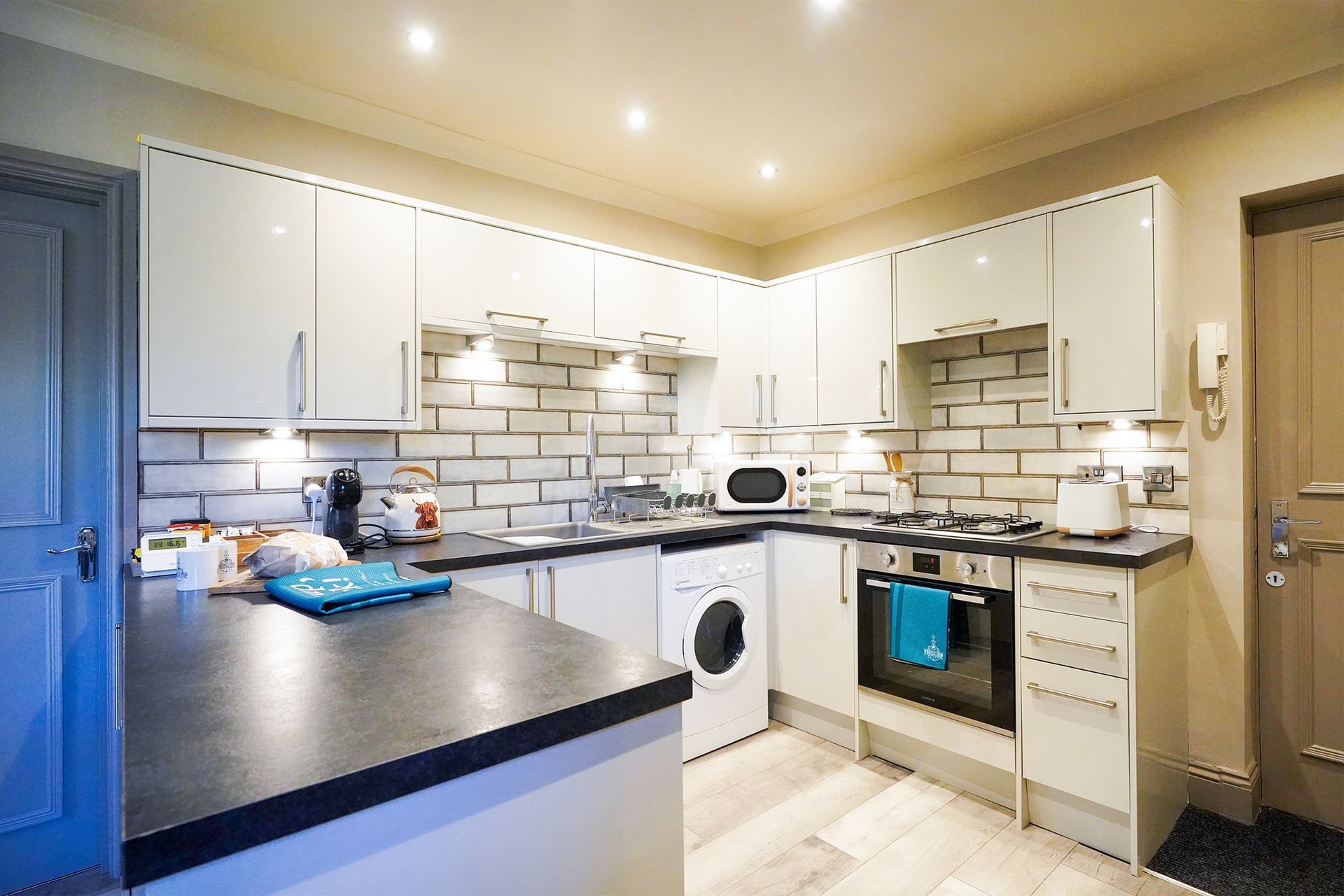 Bright modern kitchen with white cabinets, black countertops, and stainless steel appliances