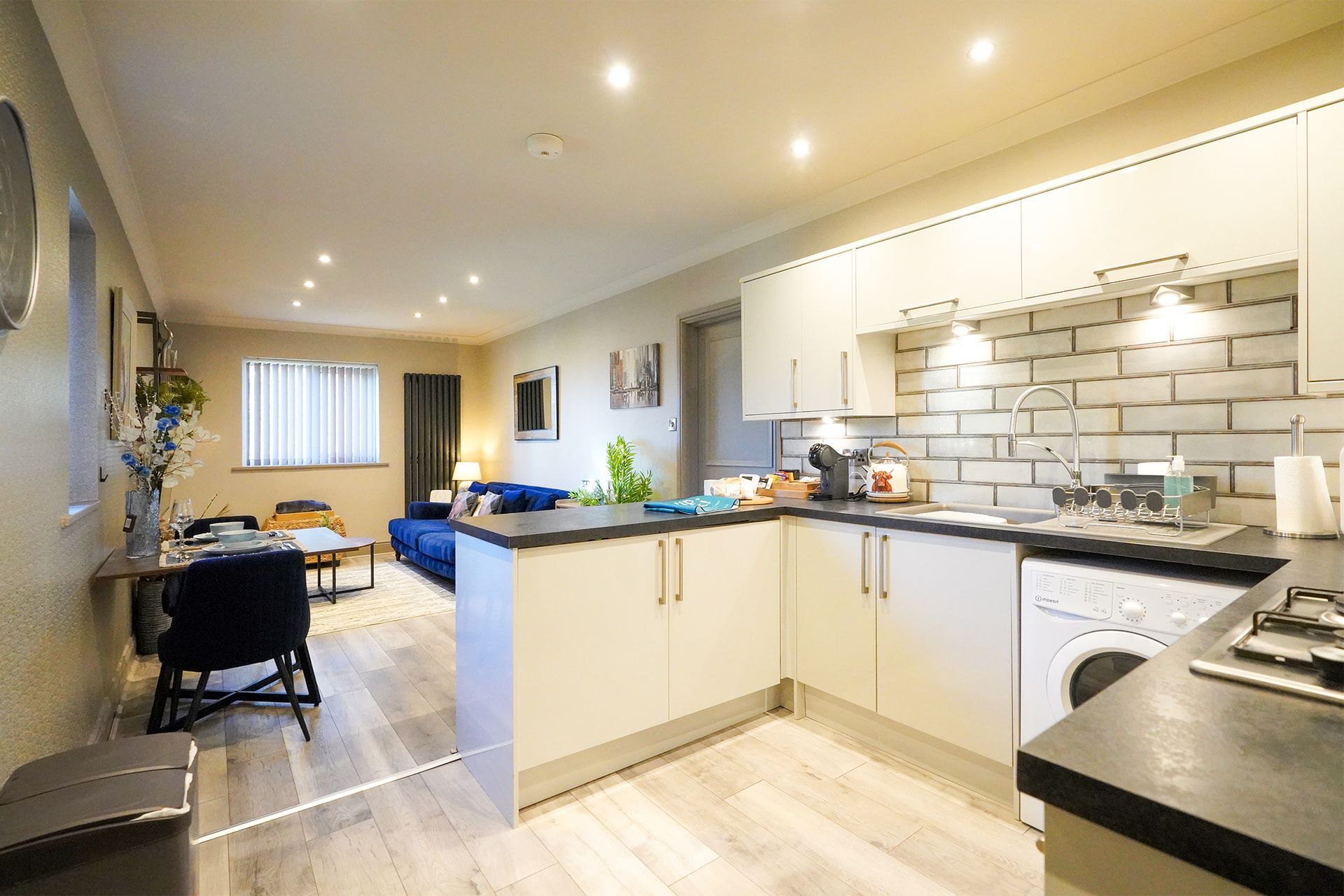 Bright open kitchen with white cabinets, black countertops, and a dining area in the background