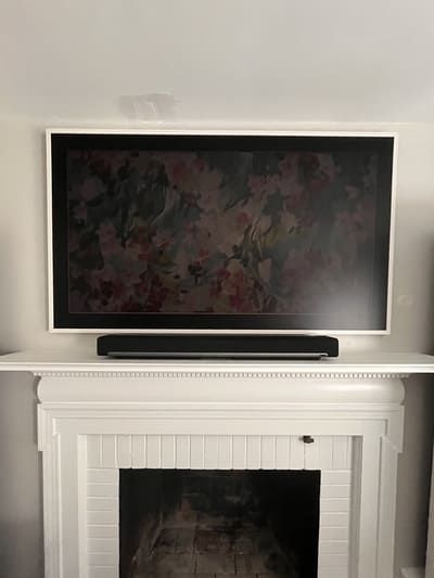 Wall-mounted TV above a white fireplace mantel in a bright room