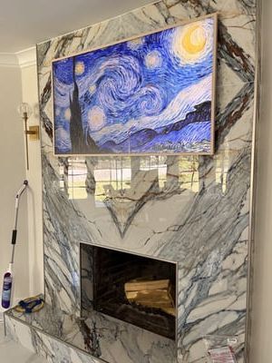 Marble fireplace with a mounted screen showing Starry Night artwork.