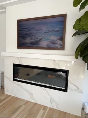 Modern fireplace with marble surround, wall art above, and a green plant on the side