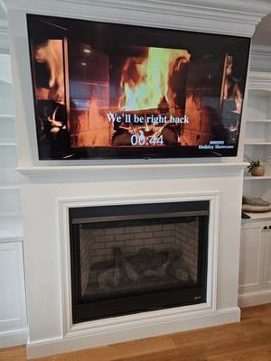 Living room with a white fireplace and a TV showing a fireplace video and “We’ll be right back” countdown