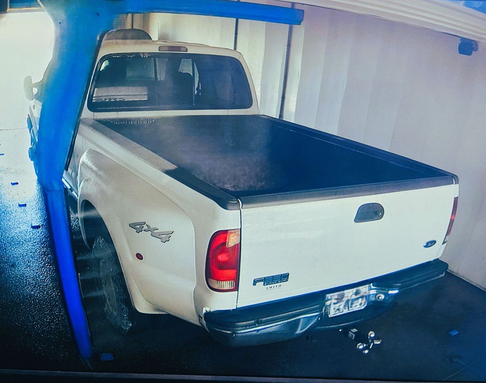 A white truck with a black bed cover is parked in a garage at pro car washes