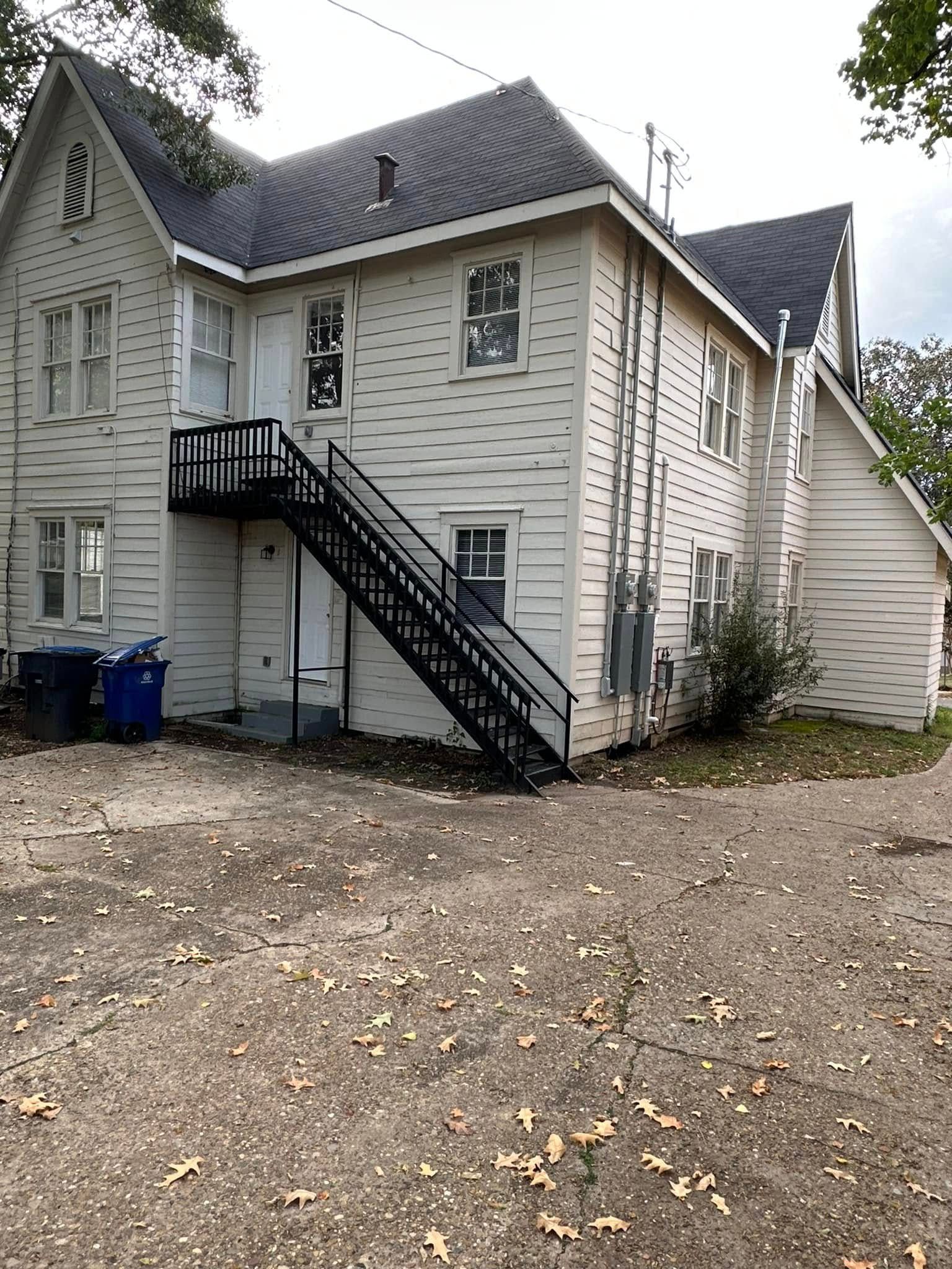 Two-story white house with black exterior stairs and a small side entry door