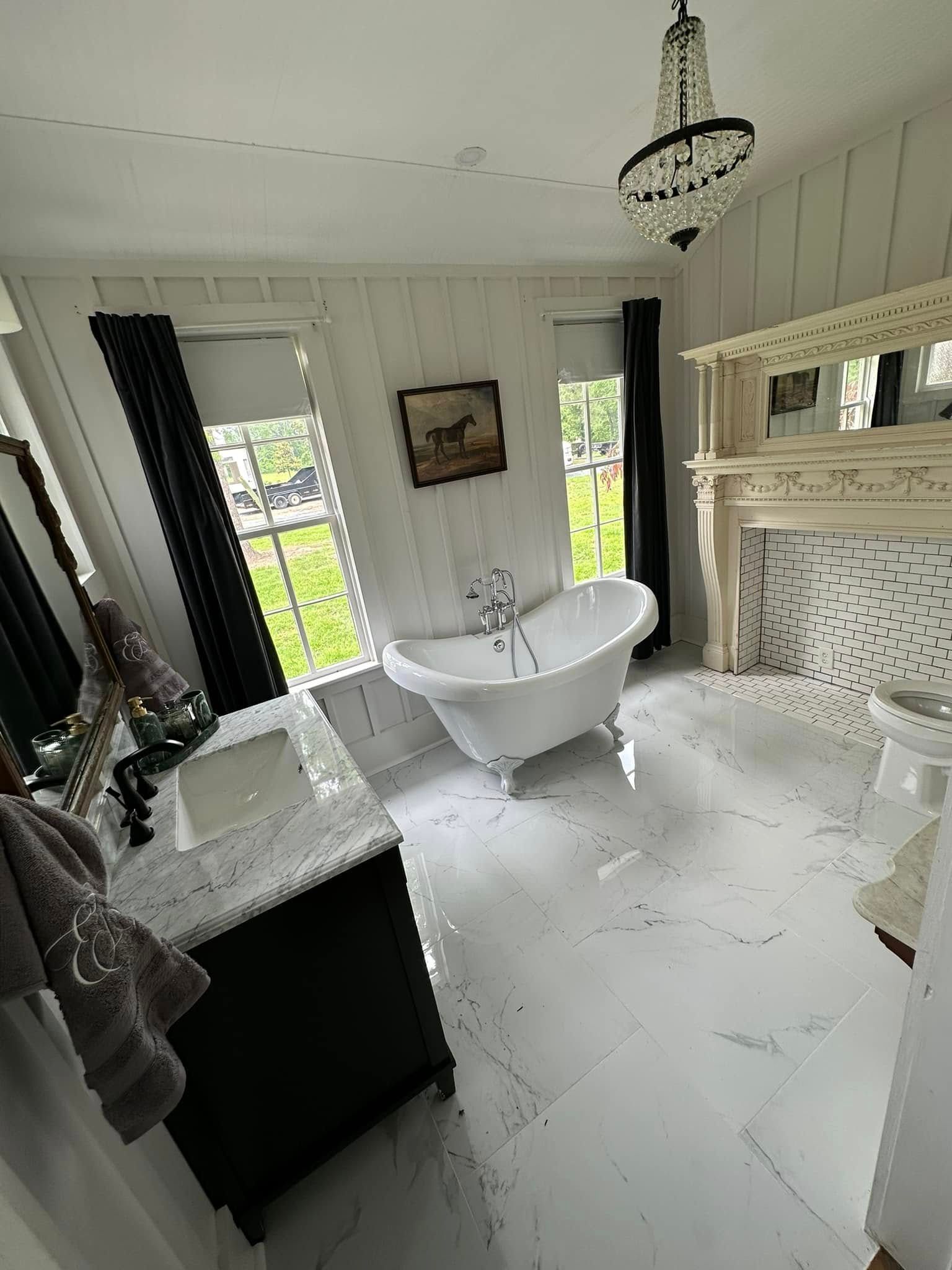 Elegant white bathroom with freestanding tub, marble sink, fireplace, and large windows