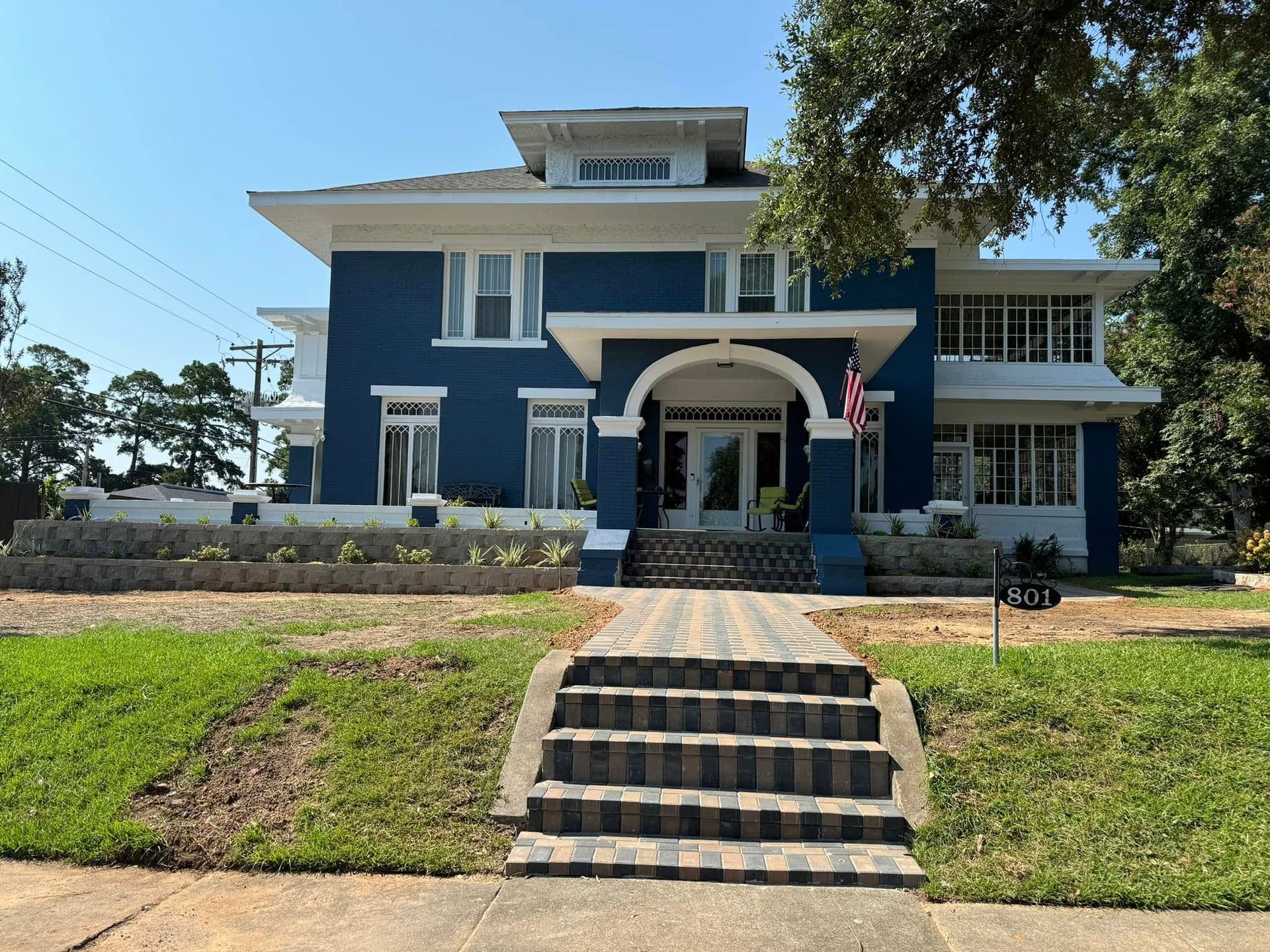 Blue two-story house with white trim and front steps under a clear sky