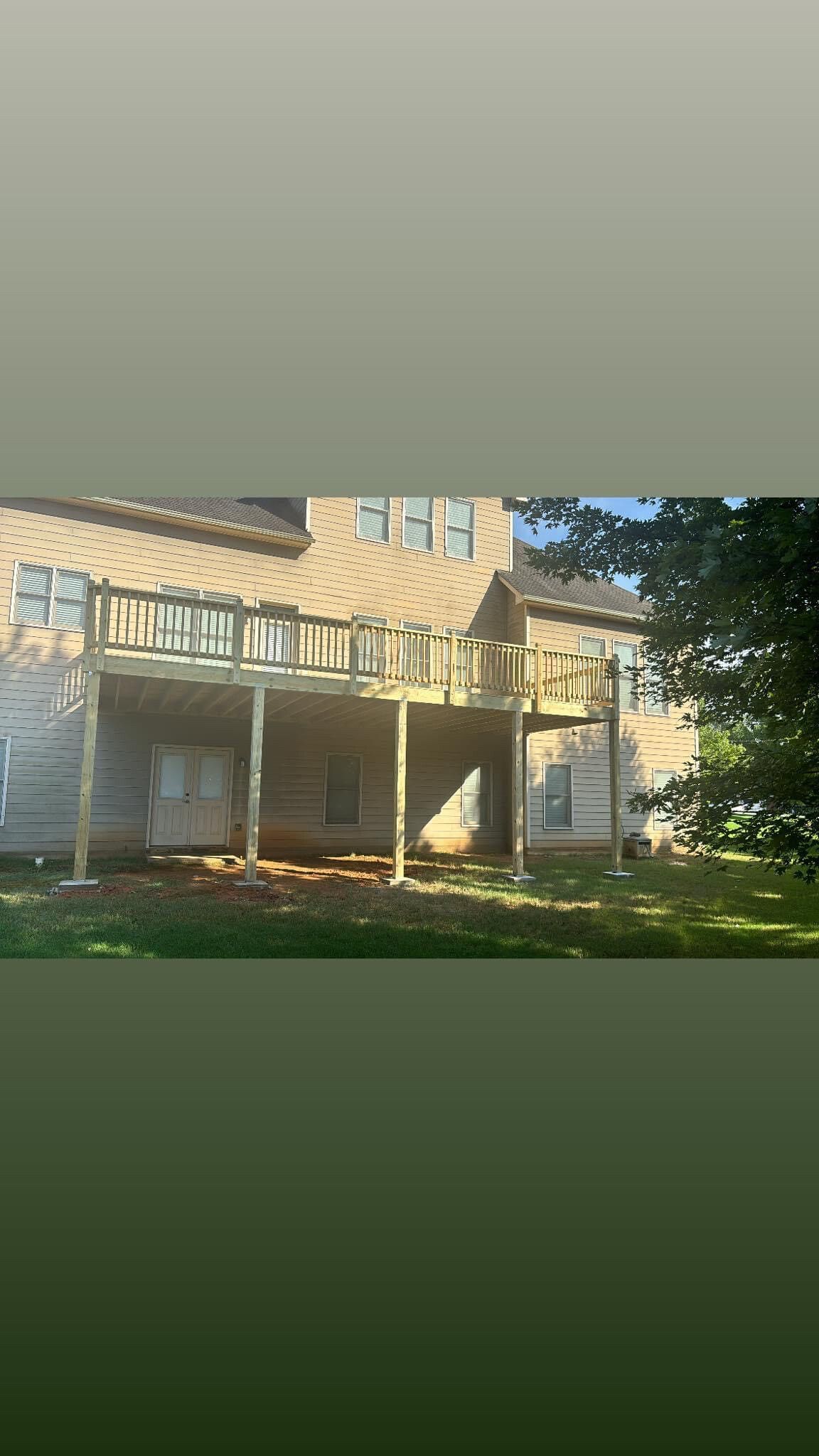 Two-story beige house with a covered porch and dark shutters, viewed from the front yard.