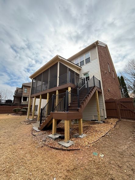 Raised house with front stairs and a brick chimney, viewed on a gravel lot under a cloudy sky