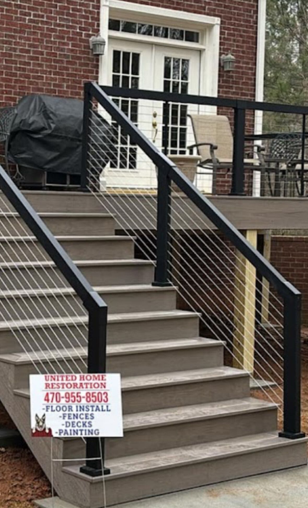 Accessible stairway with black railings and a sign advertising restoration services by a brick building