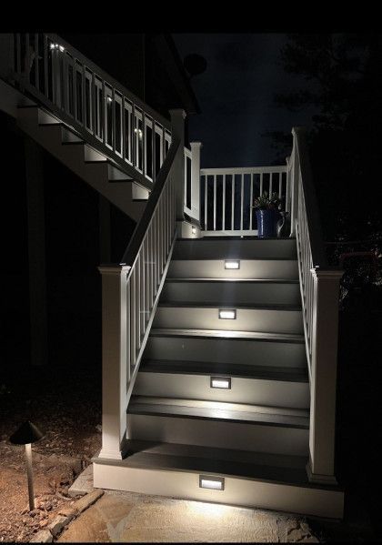 Illuminated outdoor staircase at night with white railings and small step lights