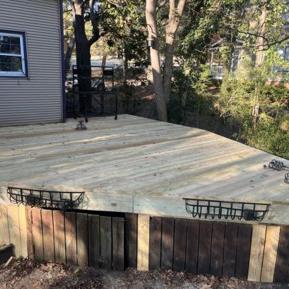 Wooden backyard deck attached to a house, with two black planter baskets along the front edge.