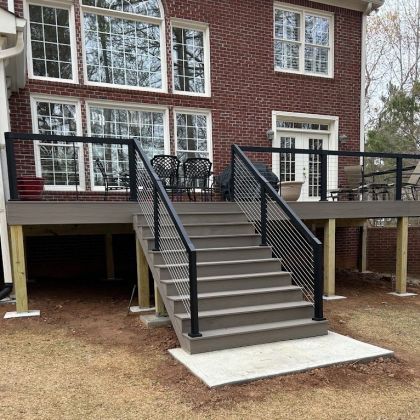 Backyard deck with central stairs, black railings, and brick house exterior.