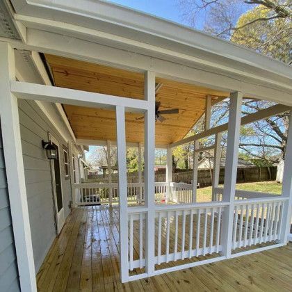 Covered white porch with railings, ceiling, and steps beside a house, viewed from the side.