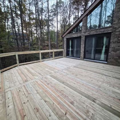 Wooden deck with railing beside a modern cabin in a wooded setting