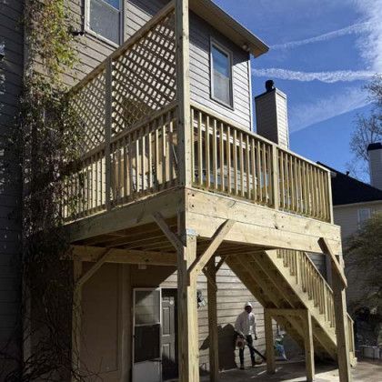 Wooden backyard deck with stairs and railing attached to a house under a blue sky
