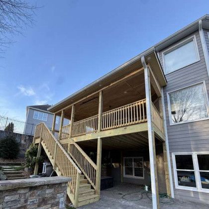 Wooden porch and staircase on the back of a gray house on a sunny day