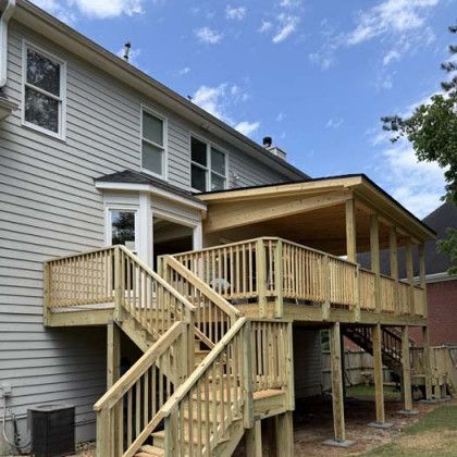 Wooden deck and stairs attached to a gray house under a blue sky