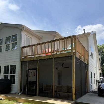 Two-story house with a wooden second-floor deck over a covered patio and garage-like lower level