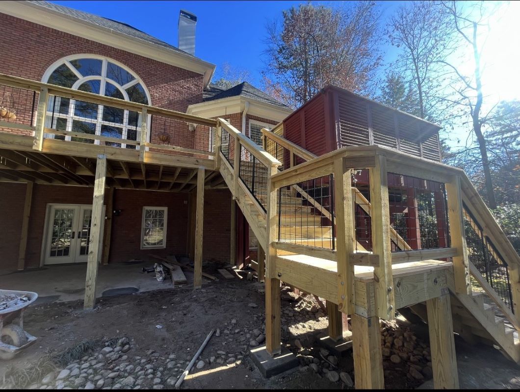 Wooden stairs and deck addition on a brick house with large arched window under bright blue sky