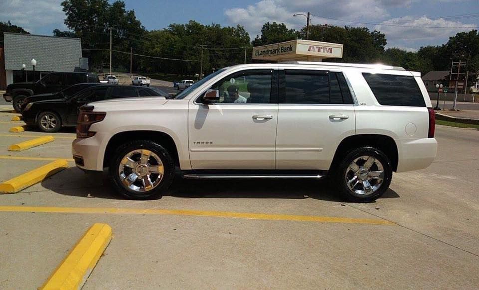 White SUV parked in a lot under a partly cloudy sky