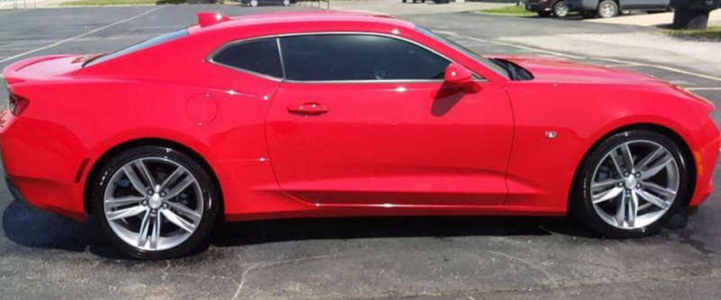 Red sports car parked on pavement, side view