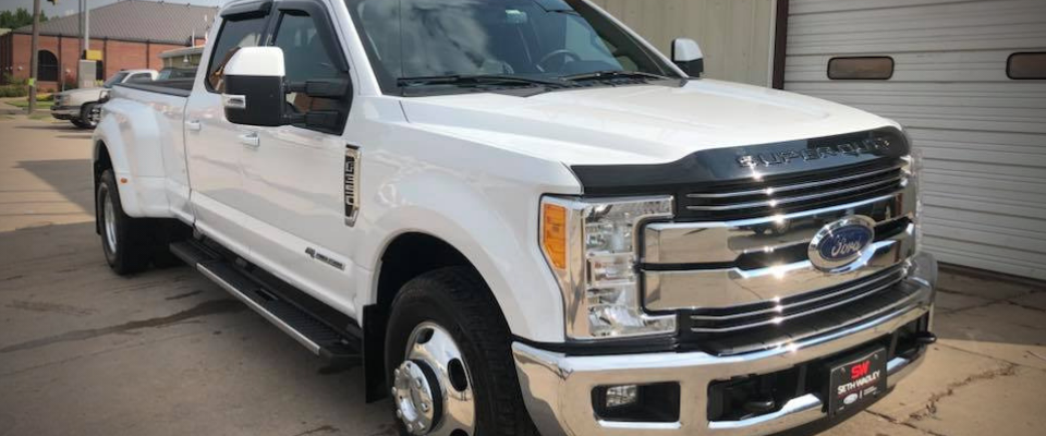 White Ford Super Duty pickup truck parked outdoors on a driveway near a garage