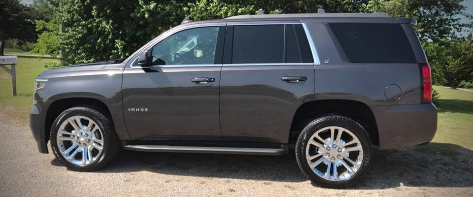 Gray SUV parked outdoors on a gravel driveway, side view