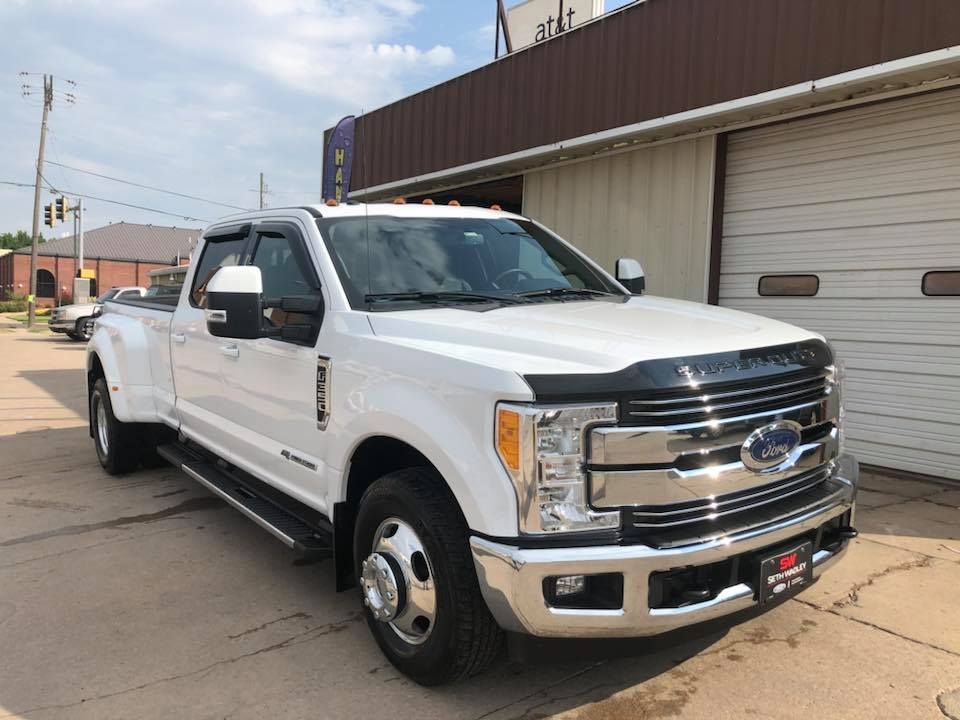 White Ford pickup truck parked beside a building on a street.