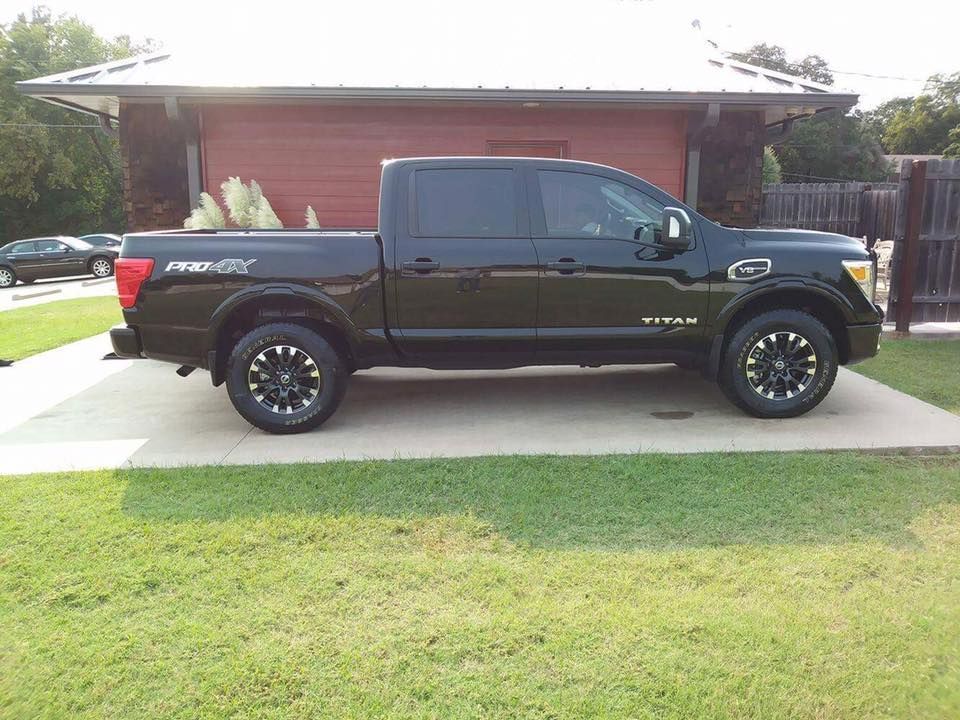 Black pickup truck parked in a driveway in front of a red house