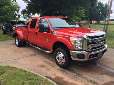 Red Ford pickup truck parked in a driveway on a wet day, with a red trailer attached.