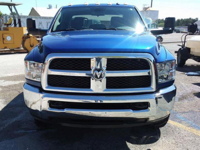 Blue Dodge Ram pickup truck front view on a sunny lot, with chrome grille and bumper.