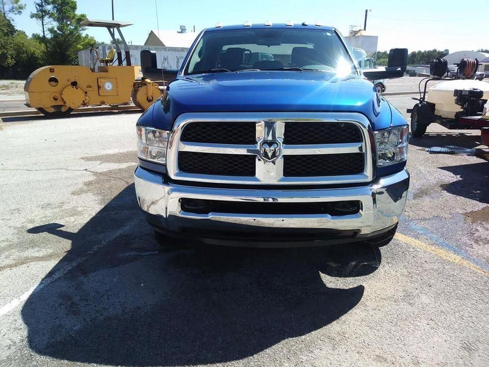 Blue Dodge Ram pickup truck parked outdoors on a sunny lot near construction equipment