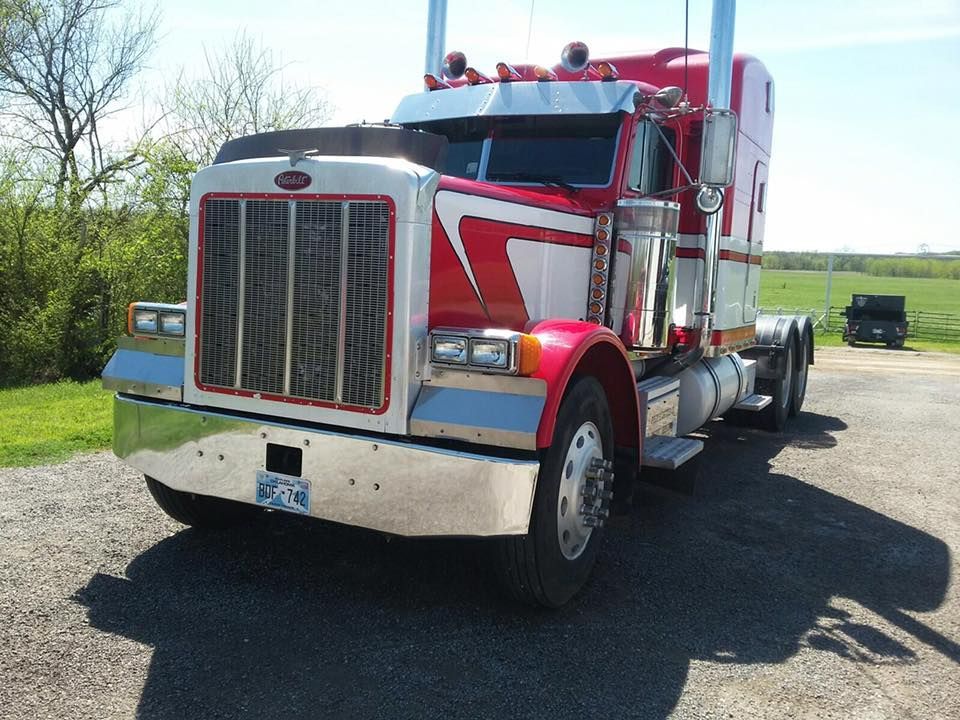 Red semi-truck parked on a gravel road in daylight