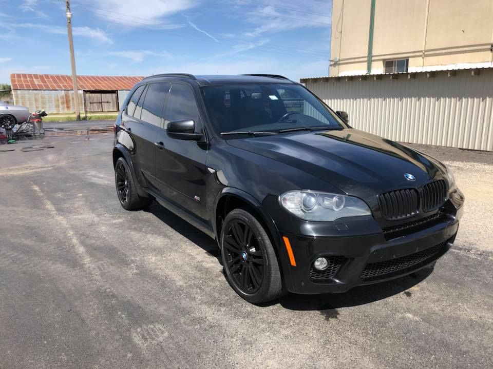 Black SUV parked in an industrial lot on a sunny day