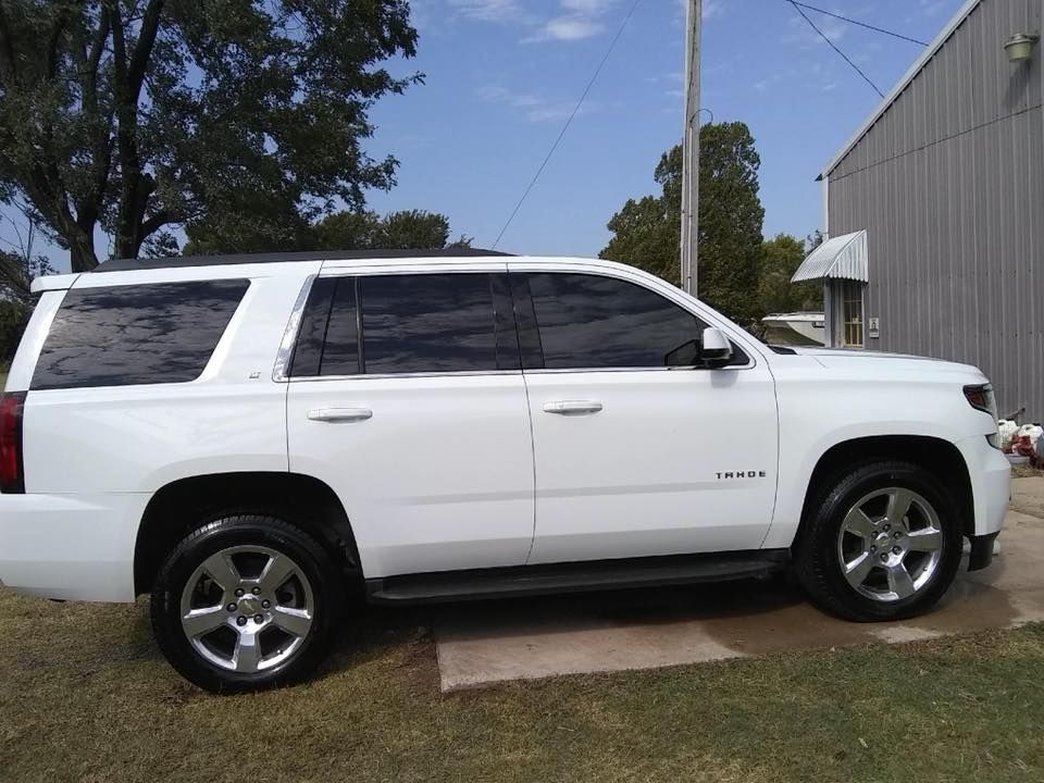 White SUV parked on grass beside a building under a clear blue sky