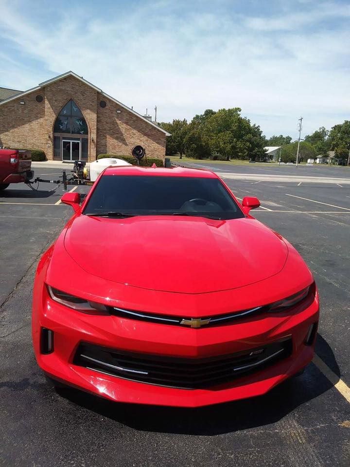 Red sports car parked in a lot in front of a brick building